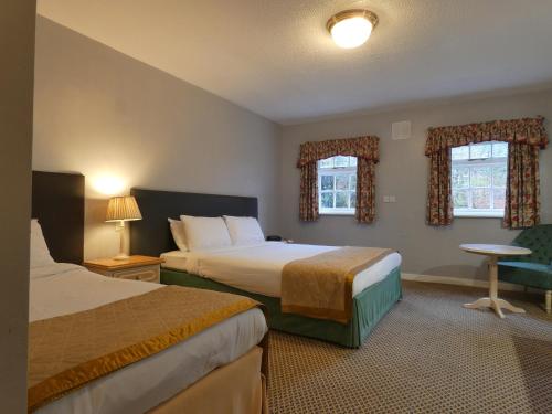 a hotel room with two beds and two windows at Marston Farm Hotel in Sutton Coldfield