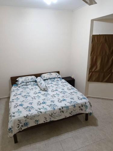 a bedroom with a bed with a blue and white comforter at NuReezal Homestay Seremban in Seremban