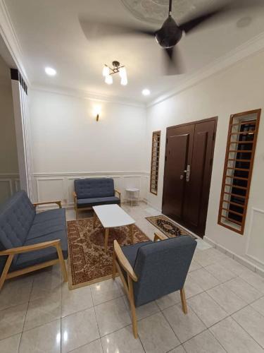 NuReezal Homestay Seremban في سِريمبان: غرفة معيشة مع كرسيين ازرق وطاولة