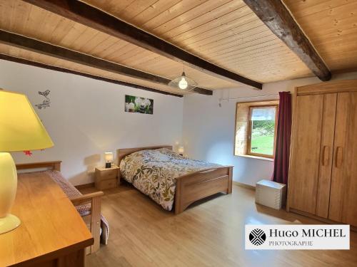 a bedroom with a bed and a desk and a window at Les volets bleus in La Chapelle-aux-Bois