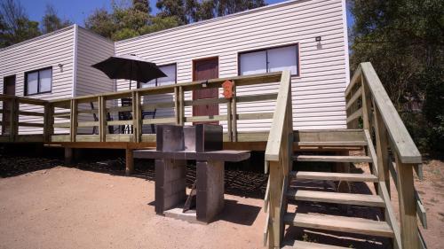 a house with a deck with an umbrella and a staircase at cabañas laguna de zapallar maitencillo in Zapallar