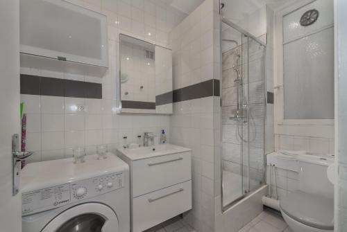 ein weißes Badezimmer mit einer Waschmaschine und einem Waschbecken in der Unterkunft Saint Michel Quartier Latin in Paris