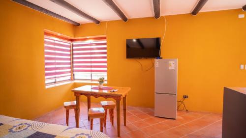 a kitchen with a table and a tv on the wall at cabañas laguna de zapallar maitencillo in Zapallar