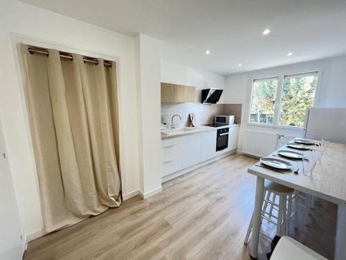 Il comprend une cuisine avec des murs blancs et du parquet. dans l'établissement Le Chantereine appartement résidentiel, à Bourgoin-Jallieu