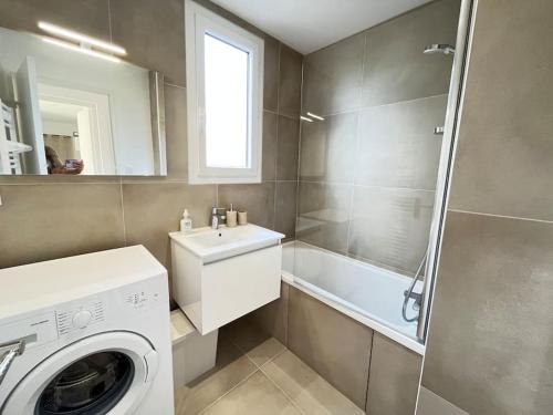 a bathroom with a sink and a washing machine at Le Chantereine appartement résidentiel in Bourgoin