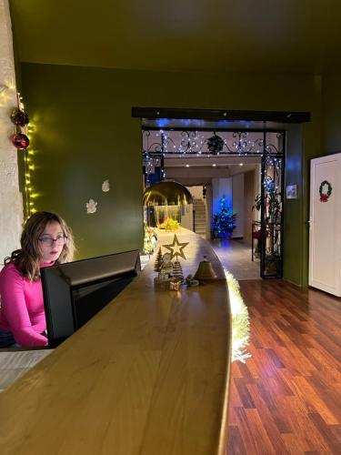 a woman sitting at a large wooden counter in a room at Hôtel Abalone - Centre Gare in Nîmes