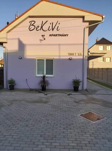 a white building with a sign on the side of it at BeKiVi apartmány in Dunajská Streda