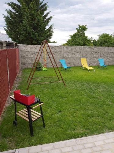 three chairs and a swing in a yard at BeKiVi apartmány in Dunajská Streda