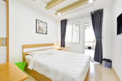 a white bedroom with a large bed and a window at Huyen Homestay in Ho Chi Minh City