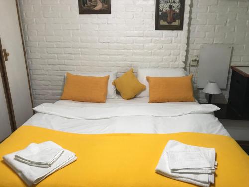 Una cama amarilla y blanca con toallas. en Studio en PH La casita de Pablo en Buenos Aires