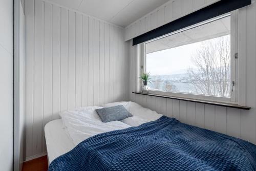 a bedroom with a bed with a blue blanket and a window at Modern apartment in the center of the island in Tromsø
