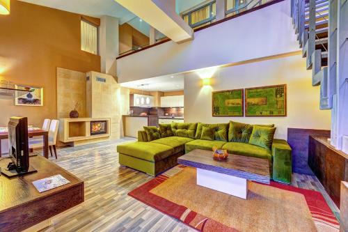 uma sala de estar com um sofá verde e uma mesa em Апартаменти Свети Трифон em Pamporovo