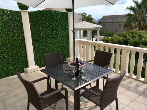 a black table with chairs and an umbrella on a porch at Apartments Villa Jadranka Adults only in Bol