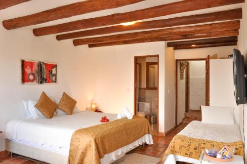 two beds in a room with wooden ceilings at Casa de Campo Hotel & Spa in Villa de Leyva