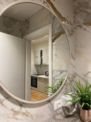 uma casa de banho com um espelho redondo numa parede de mármore em Comfort Apartament 21 em Durrës
