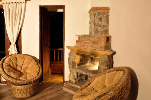 a living room with a stone fireplace and two chairs at Casa de Campo Hotel & Spa in Villa de Leyva