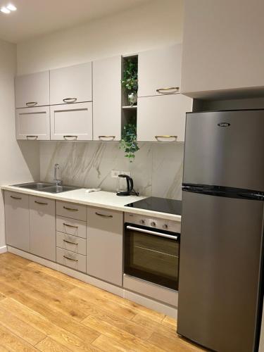 uma cozinha com armários brancos e um frigorífico de aço inoxidável em Comfort Apartament 21 em Durrës
