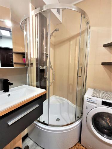 a bathroom with a shower and a sink and a washing machine at Apartament Radiostacja, dwupokojowe, parking free, klimatyzacja in Gliwice