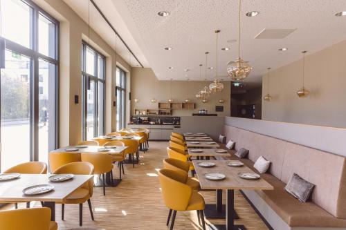 ein Restaurant mit Holztischen und gelben Stühlen in der Unterkunft Hotel Libertas elements pure in Freiburg im Breisgau