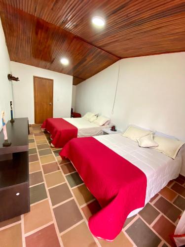 two beds in a room with red sheets at CABAÑA LOS NOGALES in San Agustín