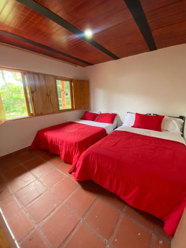 two beds in a room with red sheets at CABAÑA LOS NOGALES in San Agustín