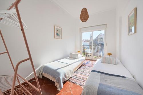 two beds in a room with a window at Central & Sunny 2BR Apt Near Beach, By TimeCooler in Setúbal