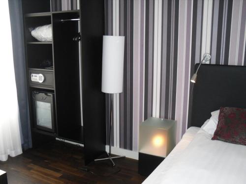 a bedroom with a bed with a lamp and a dresser at First Hotel Witt in Kalmar