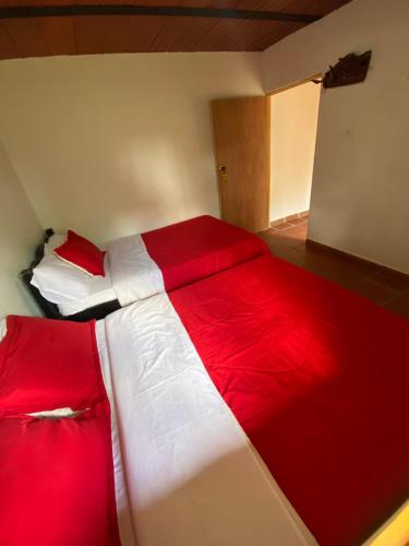 a red and white bed in a small room at CABAÑA LOS NOGALES in San Agustín