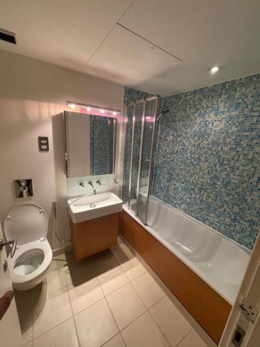 a bathroom with a toilet and a tub and a sink at Oxford Street Apartment in London
