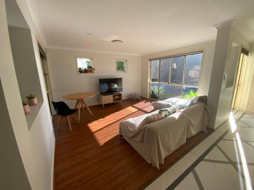 uma sala de estar com um sofá, uma mesa e uma televisão em Shared house with other guests near shopping center and theme parks em Gold Coast