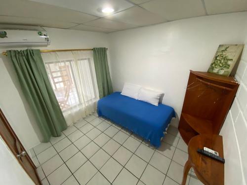 a small bedroom with a blue bed and a window at La Peregrina Galapagos B&B in Puerto Ayora