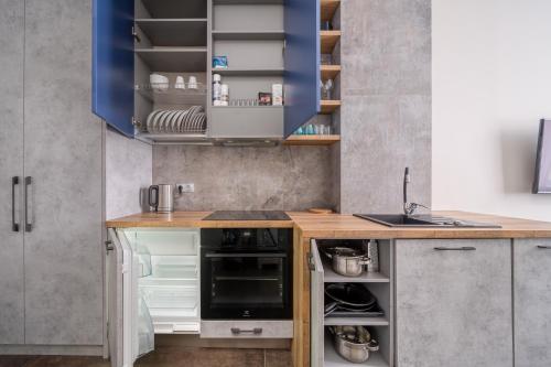 a kitchen with blue cabinets and an open refrigerator at Peaceful 1-bedroom apartment in 100m from Beach, Free Street Parking, Near Forest Park in Jūrmala
