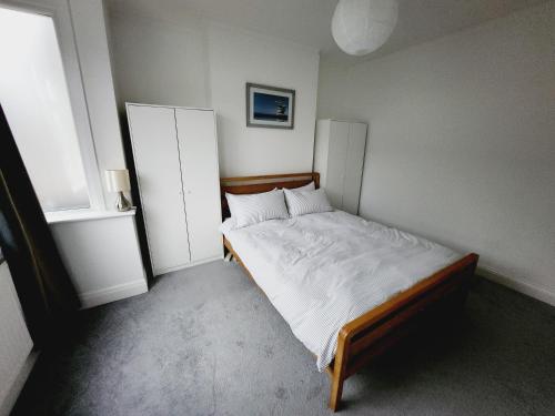 a bedroom with a bed with white sheets and a window at Guest rooms in London