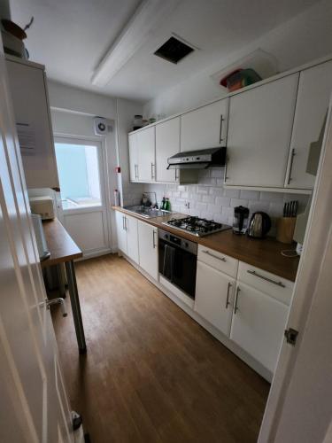 a kitchen with white cabinets and a stove top oven at Guest rooms in London