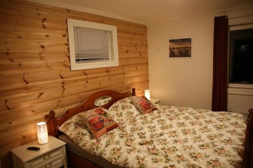 een slaapkamer met een bed met een houten muur bij Innsletta holiday home in Harstad