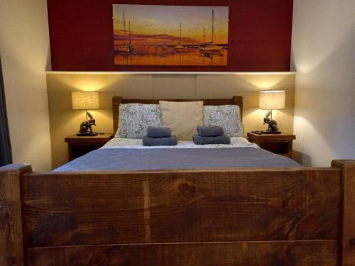 a bedroom with a large wooden bed with two lamps at Donkey & Buskins in Colchester
