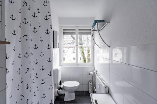ein weißes Bad mit einem WC und einem Fenster in der Unterkunft West48 Gemütliches Apartment -Blick auf Blauen See in Duisburg