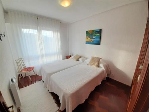 two beds in a white room with a window at Hospital de Cruces Barakaldo BEC Piso muy luminoso in Barakaldo