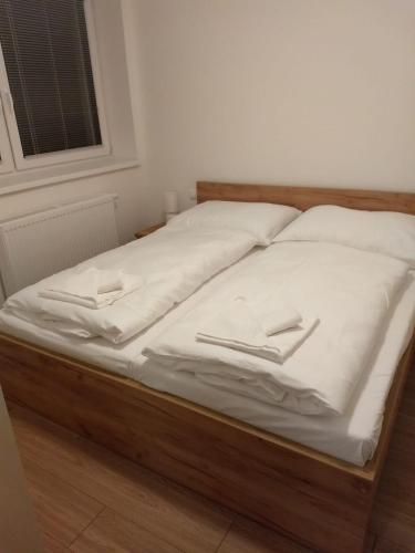 a bed with white sheets and two slippers on it at Apartman Emma in Liptovský Ján