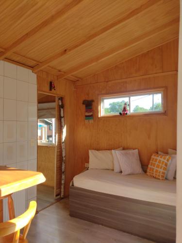 een bed in een houten kamer met een raam bij Cabañas Roka Caburgua in Pucón