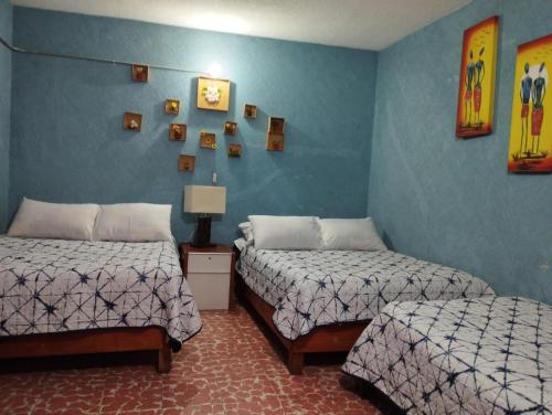 2 camas en una habitación con paredes azules en Alo México en Ciudad de México