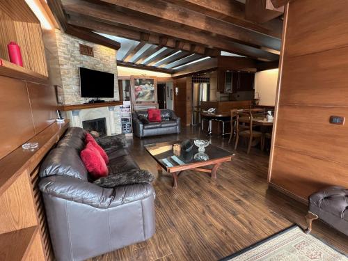 a living room with a leather couch and a table at Saint Michel Chalets in Al Arz