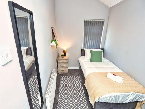 a small bedroom with a bed and a mirror at *Sleeps 9* Modern, 4 Bed House, Birmingham in Birmingham