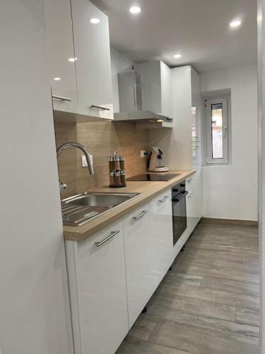 une cuisine avec des armoires blanches et un évier dans l'établissement Colmar,appart chaleureux 2 pas centre avec jardin, à Colmar