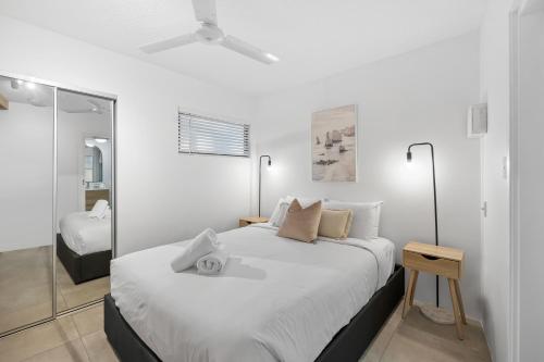 ein weißes Schlafzimmer mit einem großen Bett und einem Spiegel in der Unterkunft Beach Club Delight in Mooloolaba