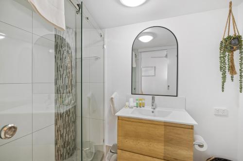 ein Bad mit einer Dusche, einem Waschbecken und einem Spiegel in der Unterkunft Beach Club Delight in Mooloolaba