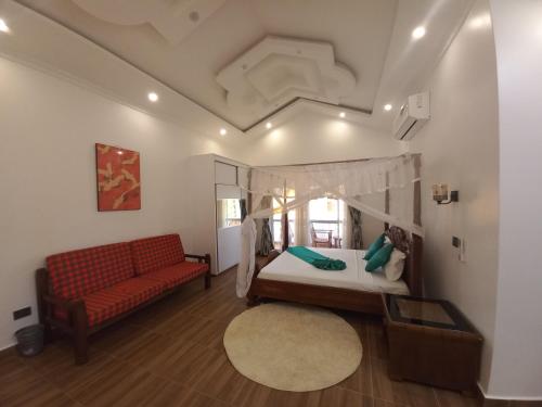 um quarto com uma cama e um sofá vermelho em Villa Duran - 5 bedrooms em Ukunda
