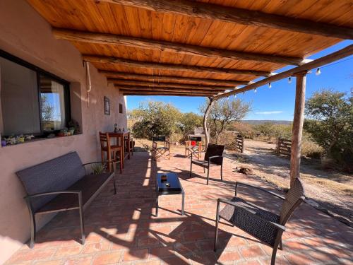d'une terrasse couverte avec des chaises et une table. dans l'établissement Cabañas Taos Pueblo, à Capilla del Monte