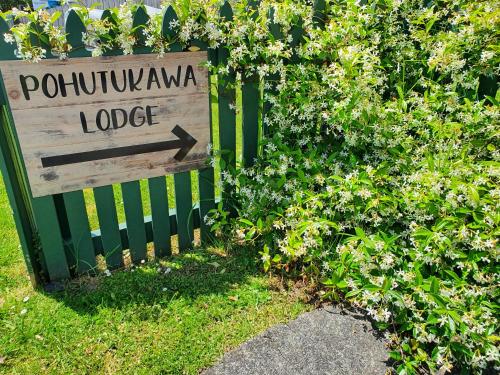 a sign that says potkunka lodge next to a fence at Pohutukawa Lodge by Orewa Beach in Orewa