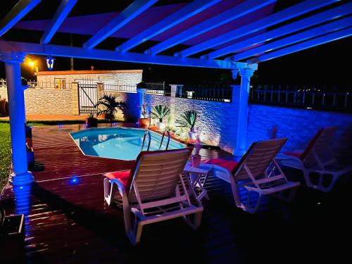 eine Terrasse mit 2 Stühlen und einem Pool in der Nacht in der Unterkunft Villa Paradis in Le François